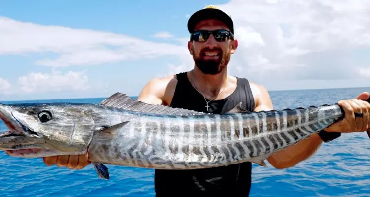 Tourists rentaing a yacht for a fishing trip in Dubai hold up a large fish they have just caught